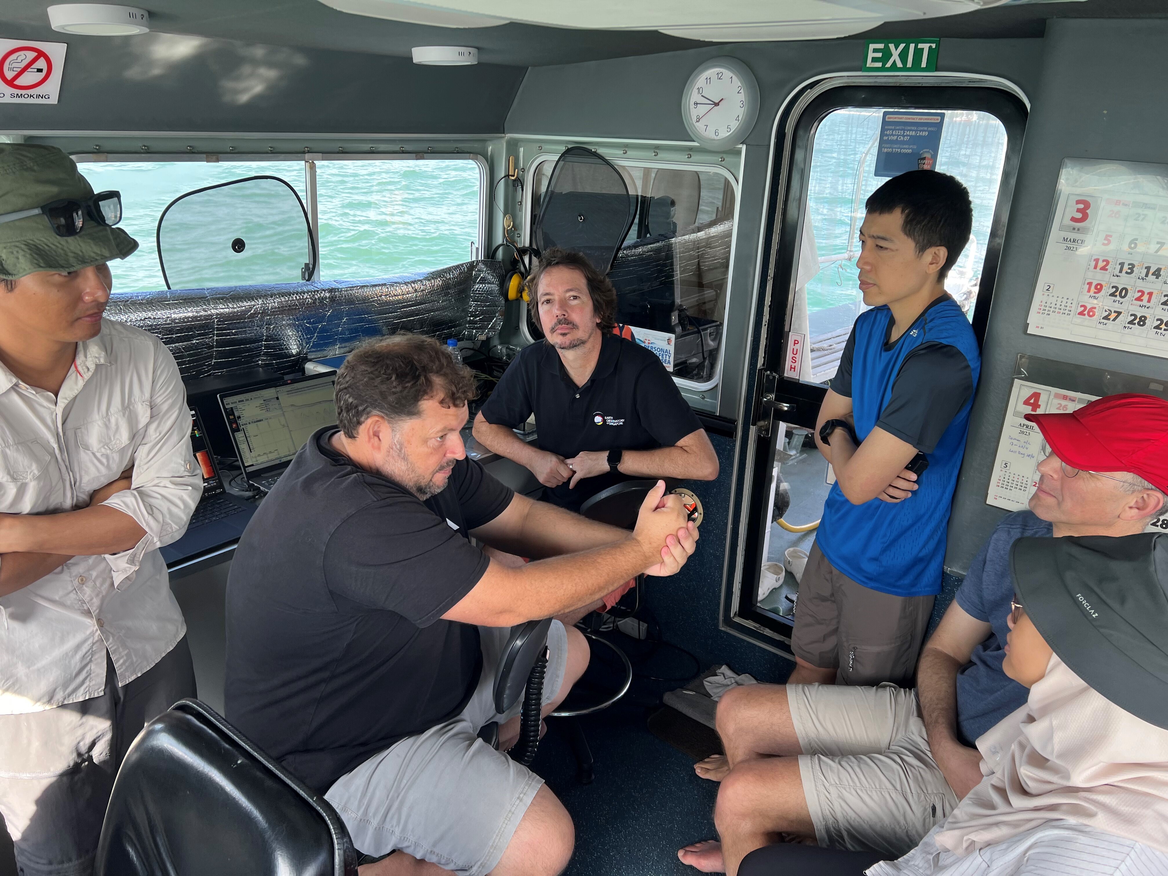 Discussion between EOS researchers, collaborators and visitor from PUB on the boat. From left to Right: Dr. Abang Nugraha (from the Coastal Lab at EOS), Mr. Doug Slougrove (University of KwaZulu-Natal), Prof. Andrew Green (University of KwaZulu-Natal), Dr. Stephen Chua (from the EOS Sea Level Research team), Prof. Uri Schattner (Haifa University) and Ms. Farzana Miswan (PUB Project Manager) (Source: Abang Nugraha/Earth Observatory of Singapore)