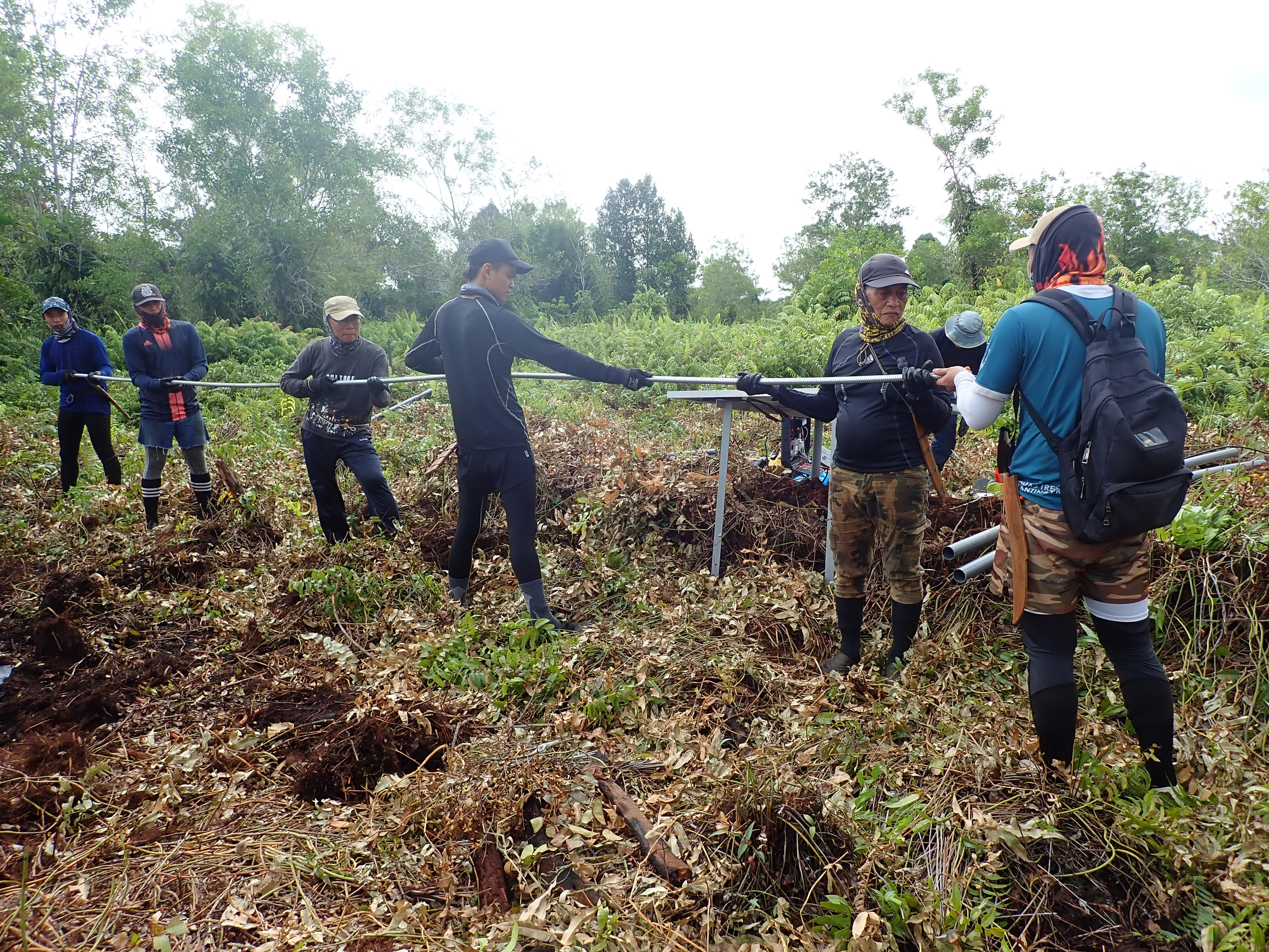 Members of the EOS Centre for Geohazard Observations and local collaborators preparing to install the GNSS station, a device that measures how fast the peatland is sinking (Source: Rino Salman/Earth Observatory of Singapore)