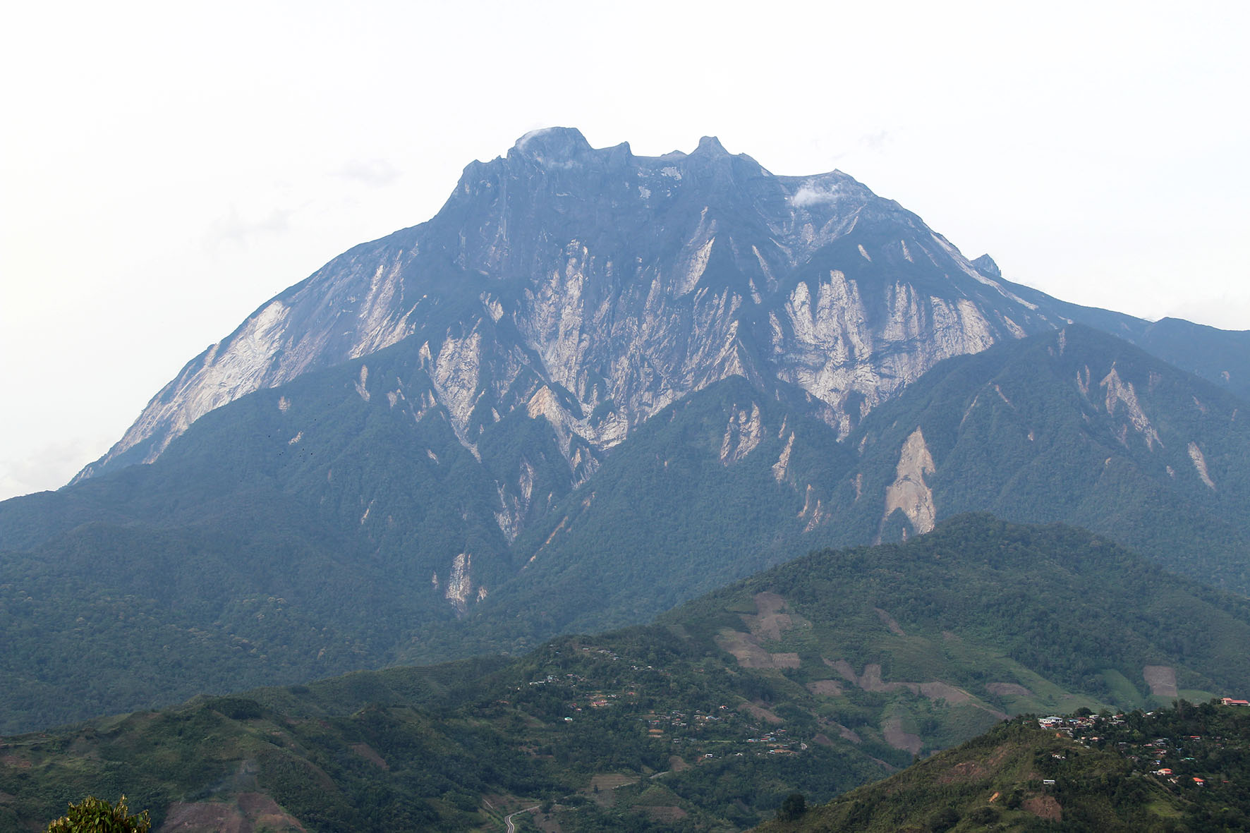 View of Mount Kinabalu from Pekan Nabalu, a small town at which tourists visiting the mountain would stop. Trails of rock debris can be seen on the slopes of the mountain where landslides had occurred (Source: Yvonne Soon)